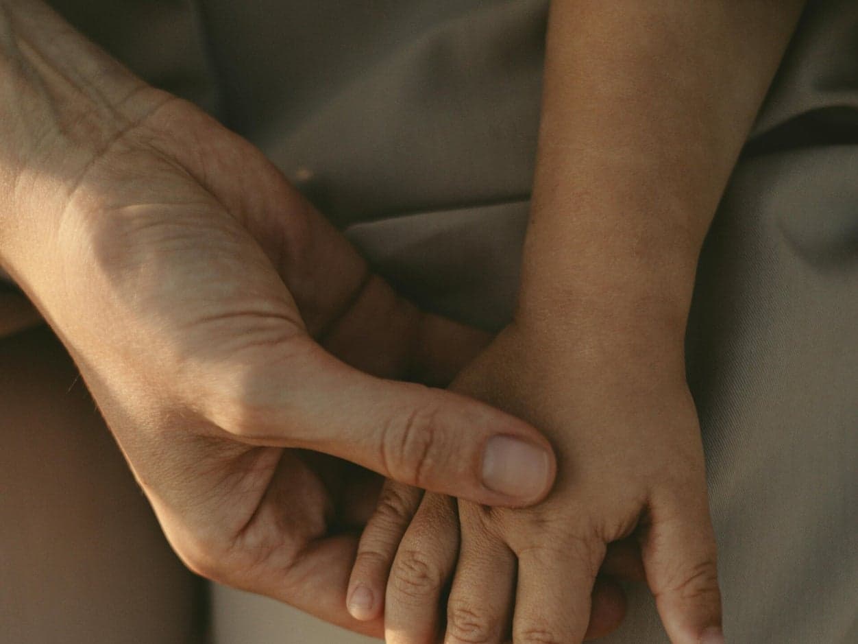 Een volwassen hand die rustig verbinding maakt met een kinderhand