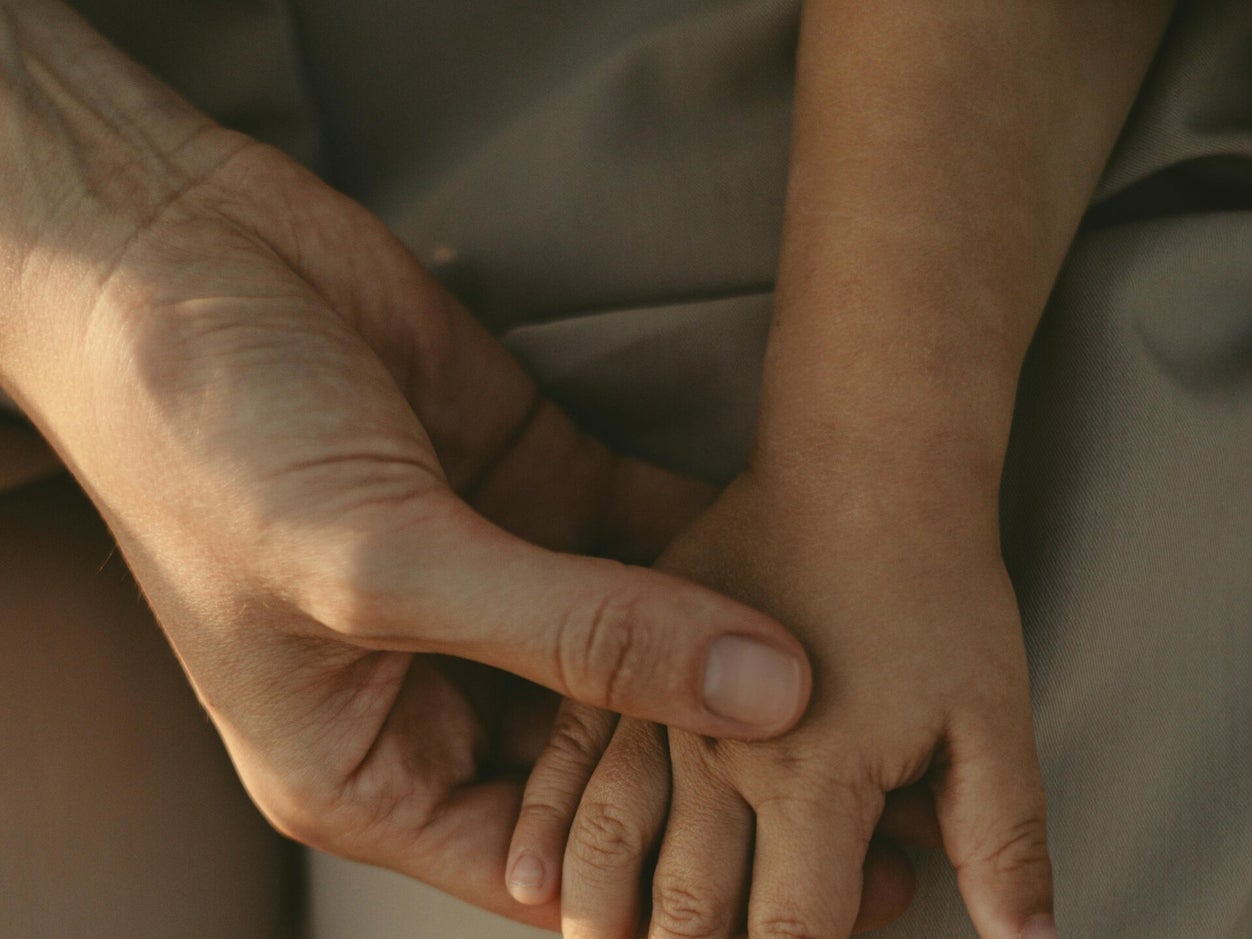 Een volwassen hand die rustig verbinding maakt met een kinderhand
